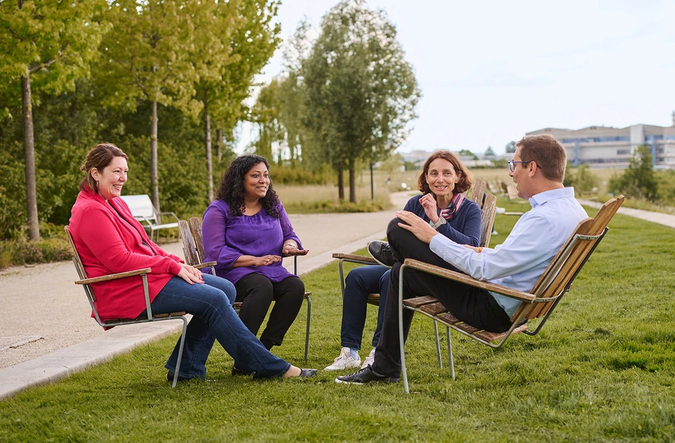 Four business people discussing while sitting in a park in the Novartis Basel campus