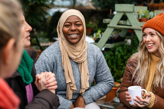 Group of warm clothed women, seated outside, smiling and laughing