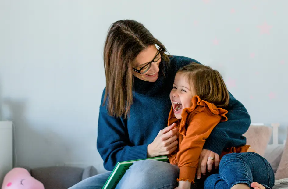 A still of a mother and daughter sharing laughter in a children`s room