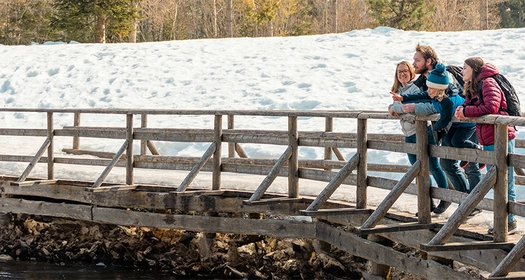 Une famille en randonnée en montagne fait une pause au bord d'un lac.