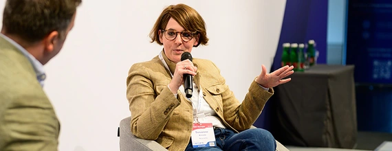 woman on stage talking and holding a microphone