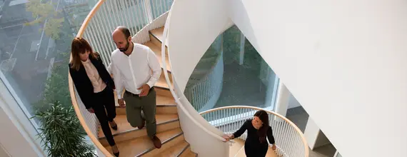 Profesionistë që ecin në një shkallë spirale në një ndërtesë zyrash