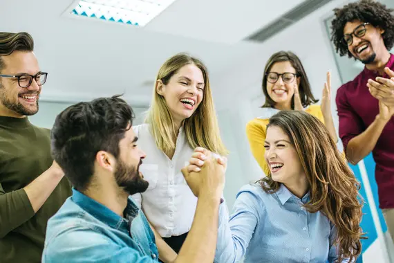 Group of coworkers celebrating success with a strong handshake in office
