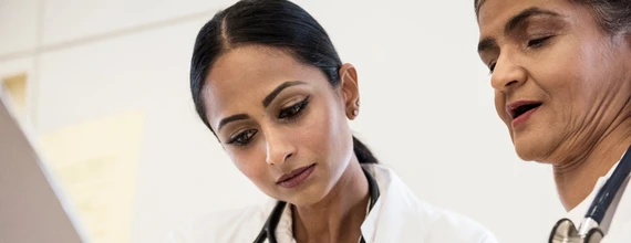 Foto de duas mulheres médicas olhando para baixo com foco em um ponto. 
